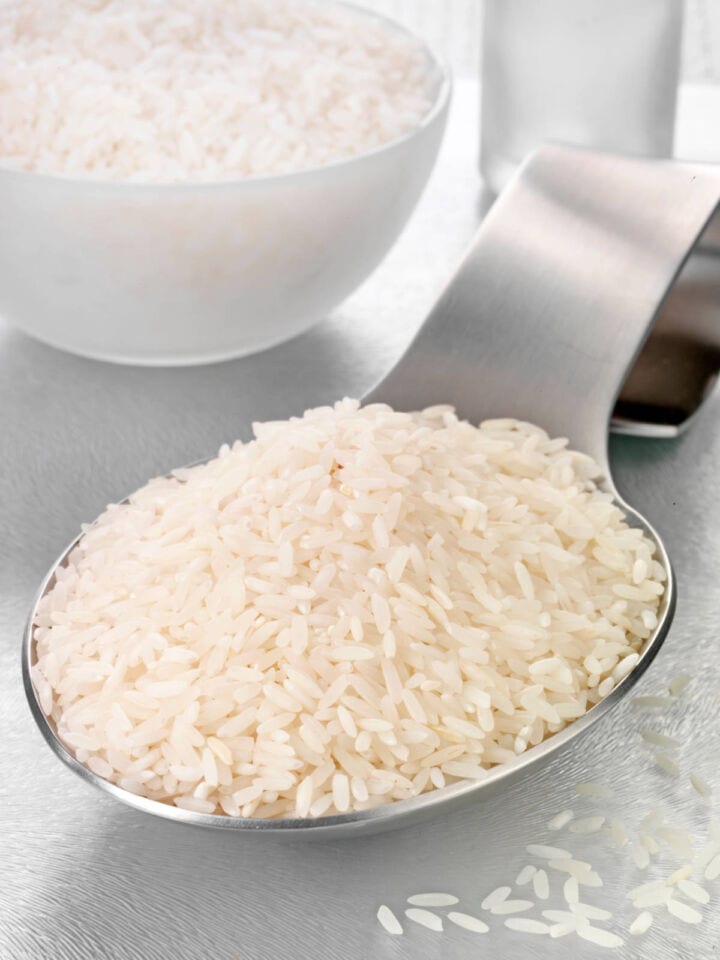 Measuring jasmine rice with metal scoop.