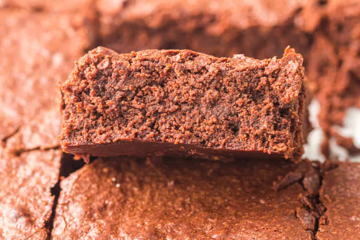Close-up of a thick, fudgy brownie showing moist crumb and crackly top.
