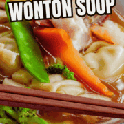 Bowl of subgum wonton soup with dumplings, shrimp, veggies, chopsticks on rim.