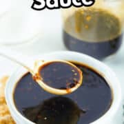 A white bowl filled with dark teppanyaki sauce, with a spoon lifting some sauce. Behind it is a jar of sauce and ingredients on a white surface. Text reads “TEPPANYAKI Sauce” and “smellslikedelish.com”.