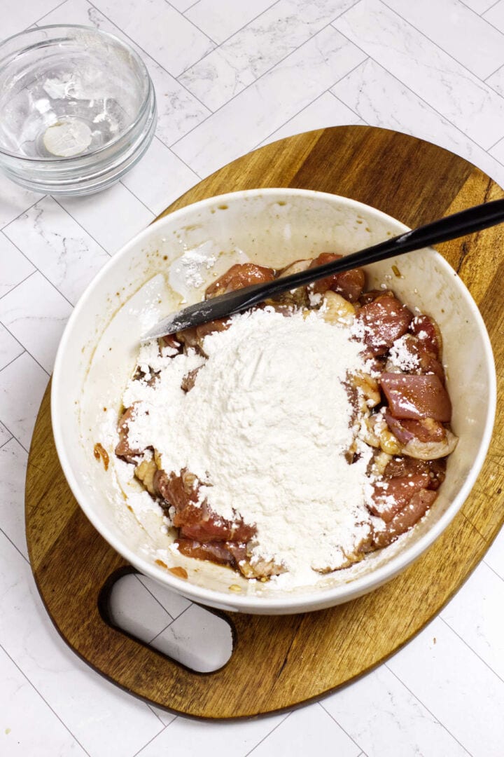 Marinated chicken topped with cornstarch and flour before tossing.