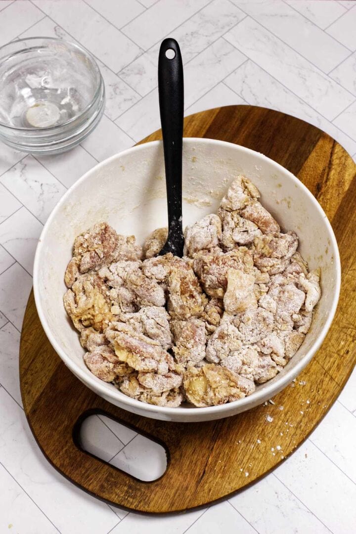 Coated chicken pieces resting in a bowl before frying.