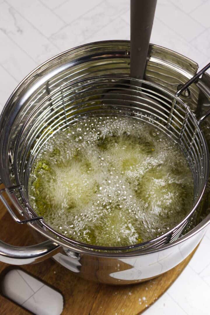 Chicken frying in hot oil during the first fry.