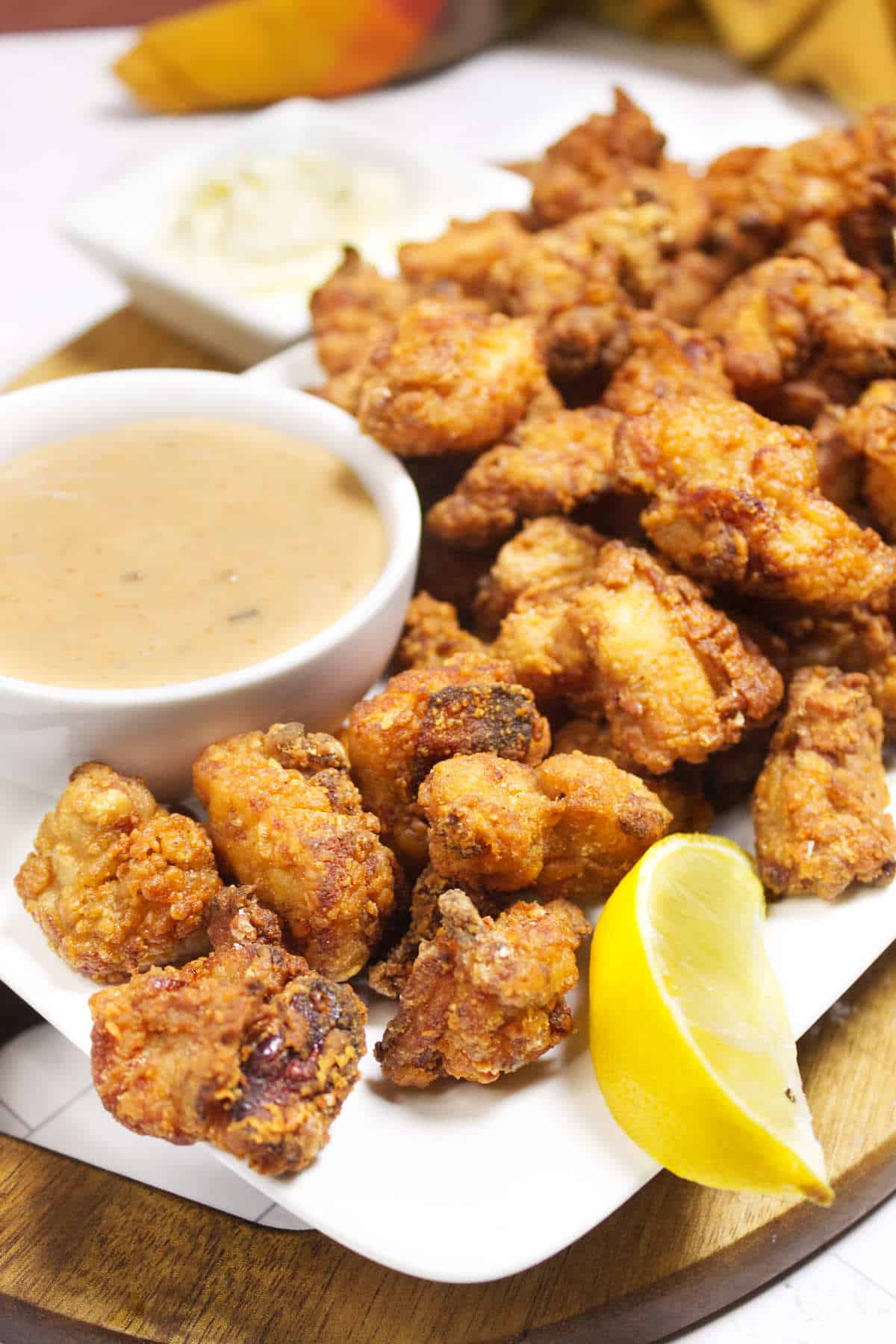 A plate of golden chicken karaage served with lemon wedges and dipping sauces.