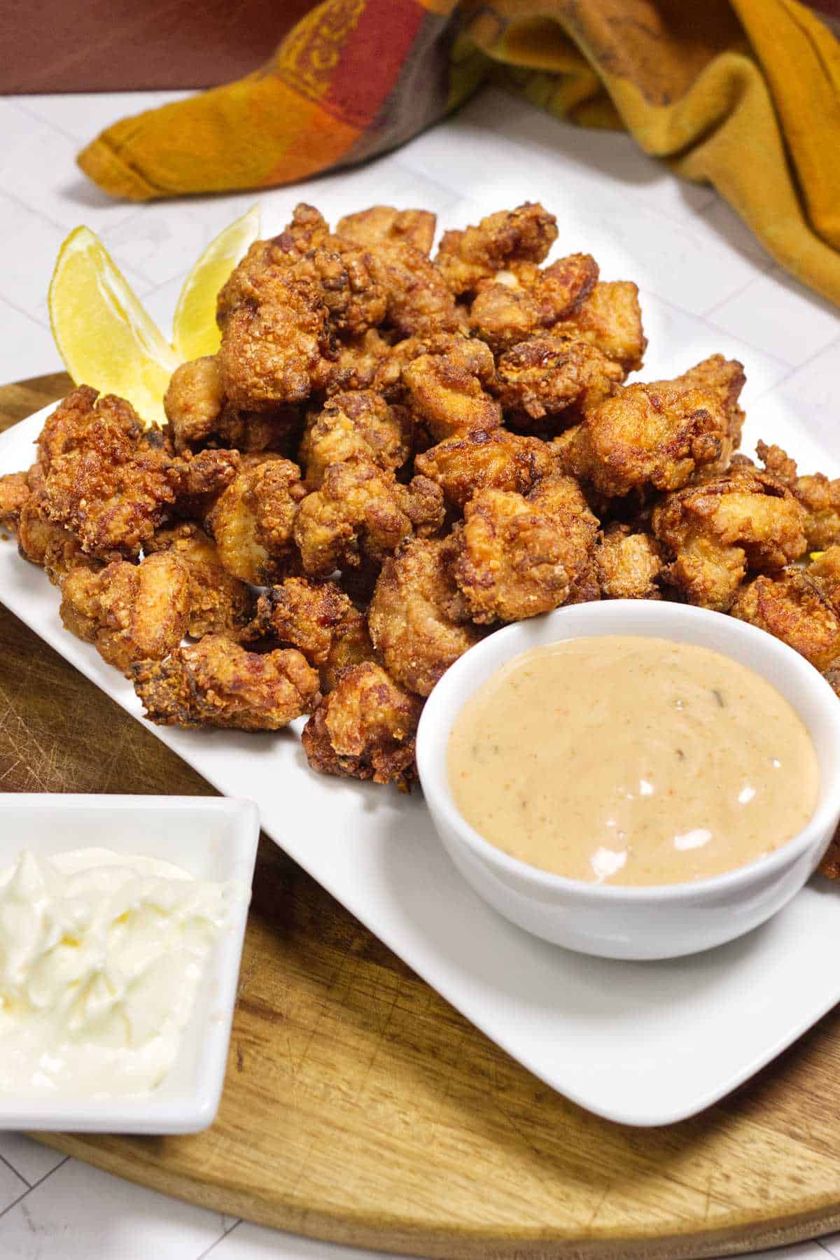 Chicken karaage on a platter with lemon wedges and dipping sauce.
