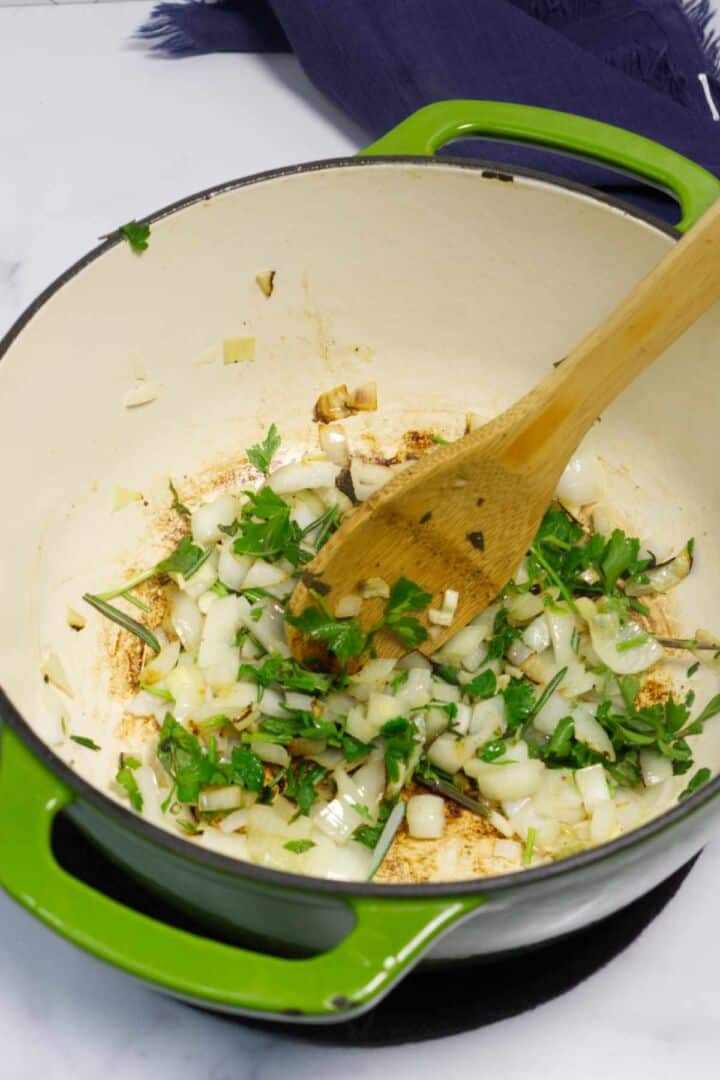 Onions and herbs sautéing in a Dutch oven.