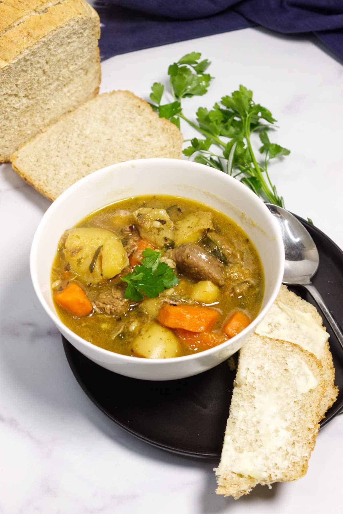 Irish lamb stew served in a bowl with bread on the side.