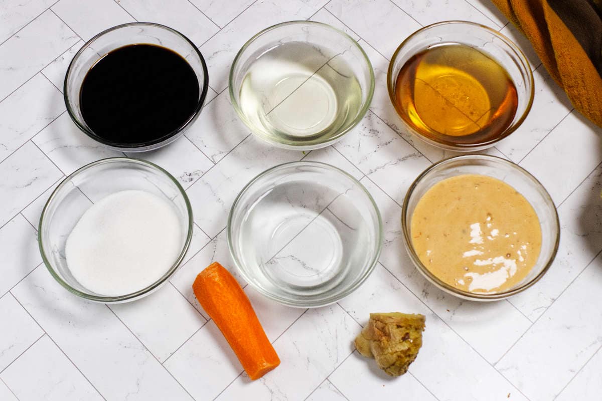 Ingredients for Japanese steakhouse ginger dressing including carrot, ginger, soy sauce, rice vinegar, and dressing base.