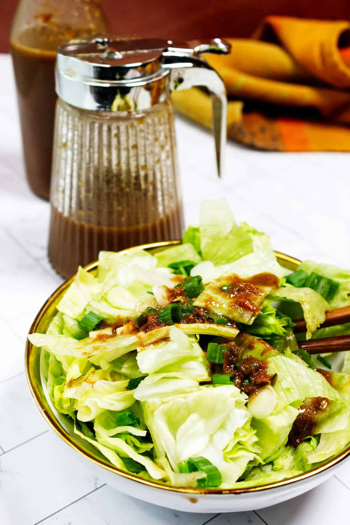 Japanese ginger salad dressing served on iceberg lettuce with scallions in a bowl.