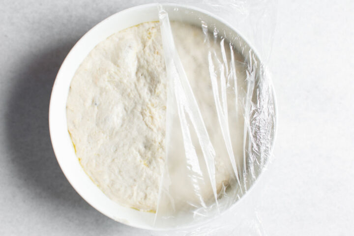 A bowl containing proofing bolillo dough in a bowl for the first proof.