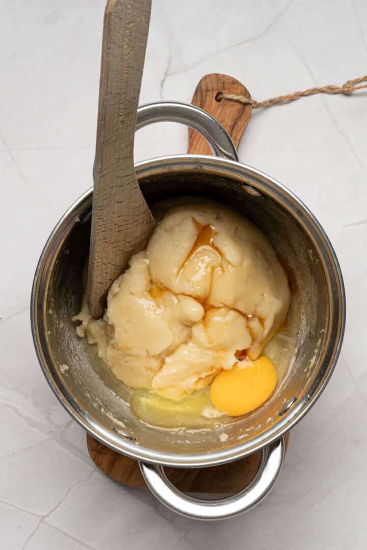 Mixing egg and vanilla into warm churro dough until combined.