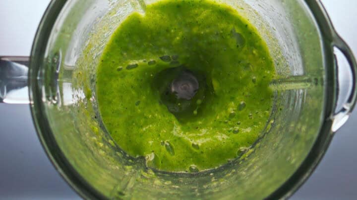 Blended poblano, cilantro, garlic, and greens mixture for arroz verde in a blender.