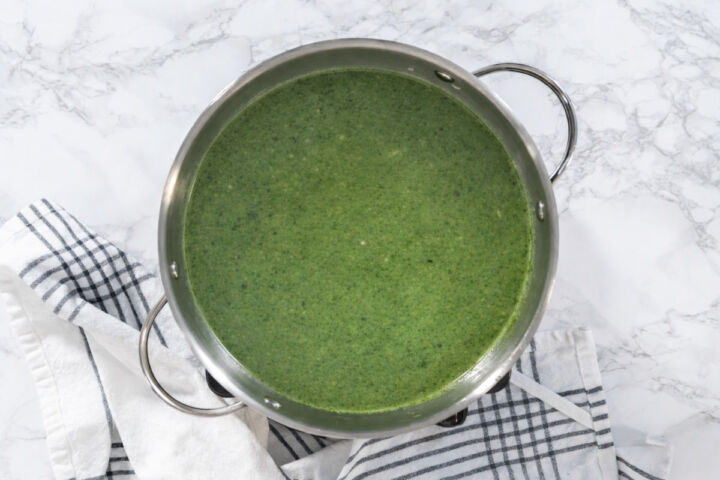 Green poblano mixture added to toasted rice in a skillet and being stirred to coat.