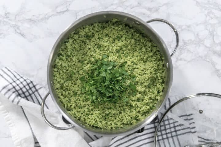 Fluffy arroz verde in a pot with chopped cilantro after resting and fluffing.