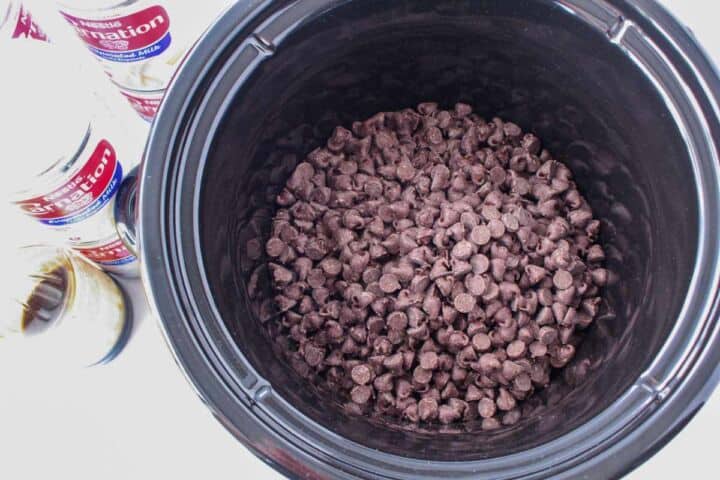 Chocolate chips added to a slow cooker for Mexican hot chocolate.