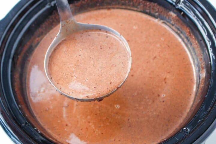 Smooth Mexican hot chocolate being ladled from a slow cooker.