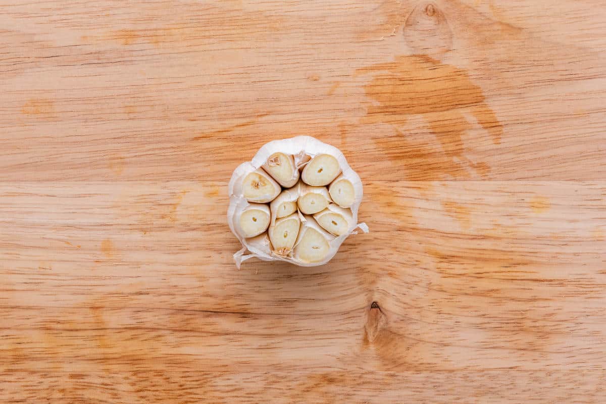 A whole garlic bulb with the top cut off to expose the cloves.