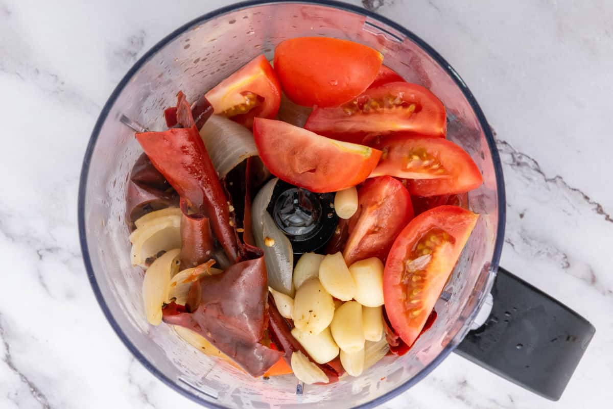 Tomatoes, chiles, garlic, and onion added to a blender with broth.