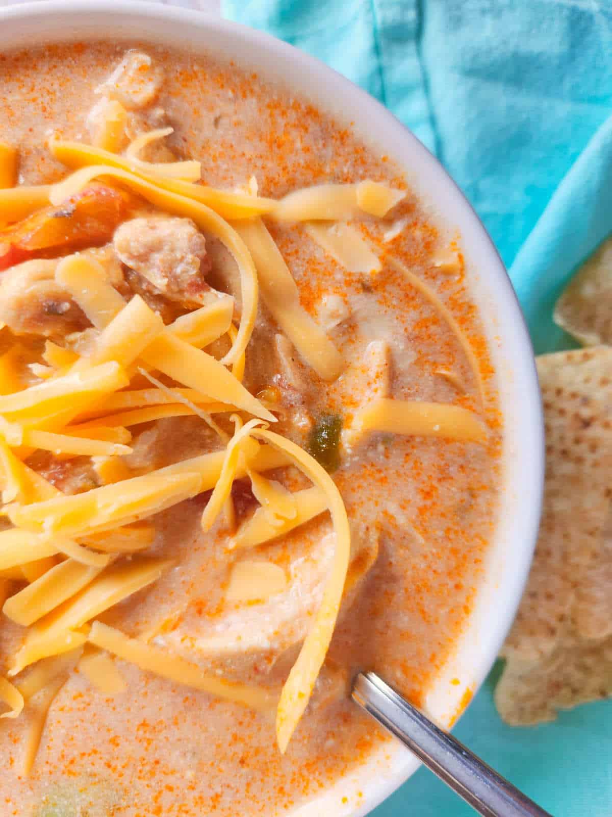 Close up of southwest chicken tortilla soup with melted cheese and visible chunks of chicken in broth.