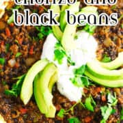 Chorizo and black beans topped with avocado, sour cream, and cilantro in a skillet.