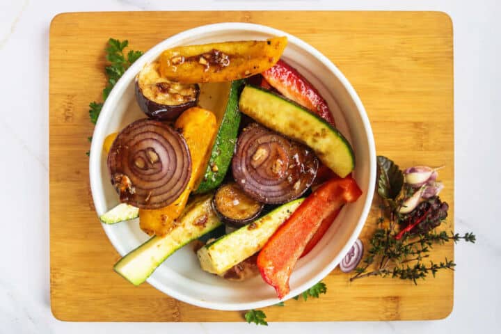 Bowl of marinated zucchini, bell peppers, red onion, and eggplant before grilling.