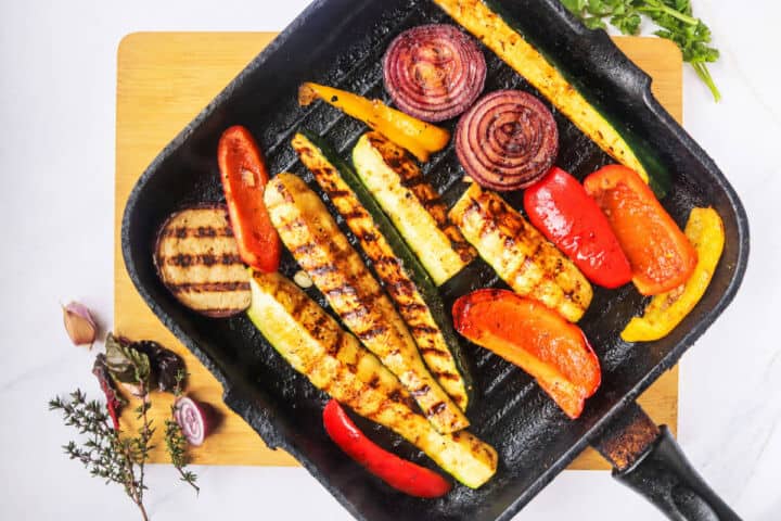 Zucchini, bell peppers, red onion, and eggplant cooking in a hot grill pan.