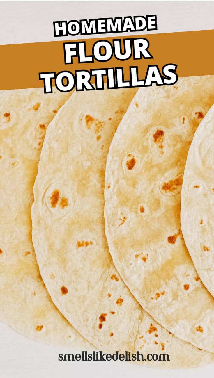 Four homemade flour tortillas overlap on a light surface.