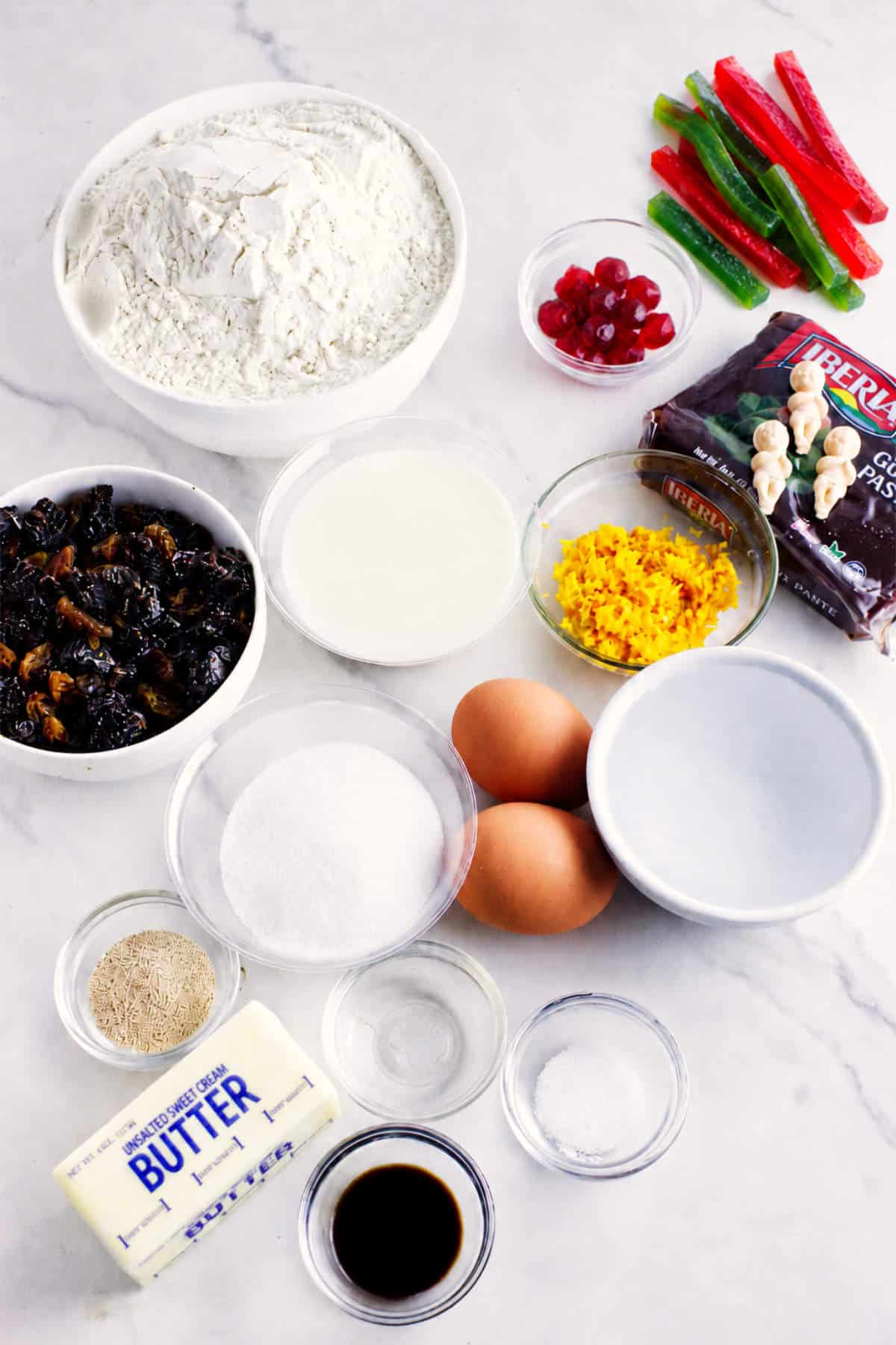 Ingredients for Rosca de Reyes, including flour, eggs, butter, yeast, orange zest, candied fruit, and candied watermelon rind.