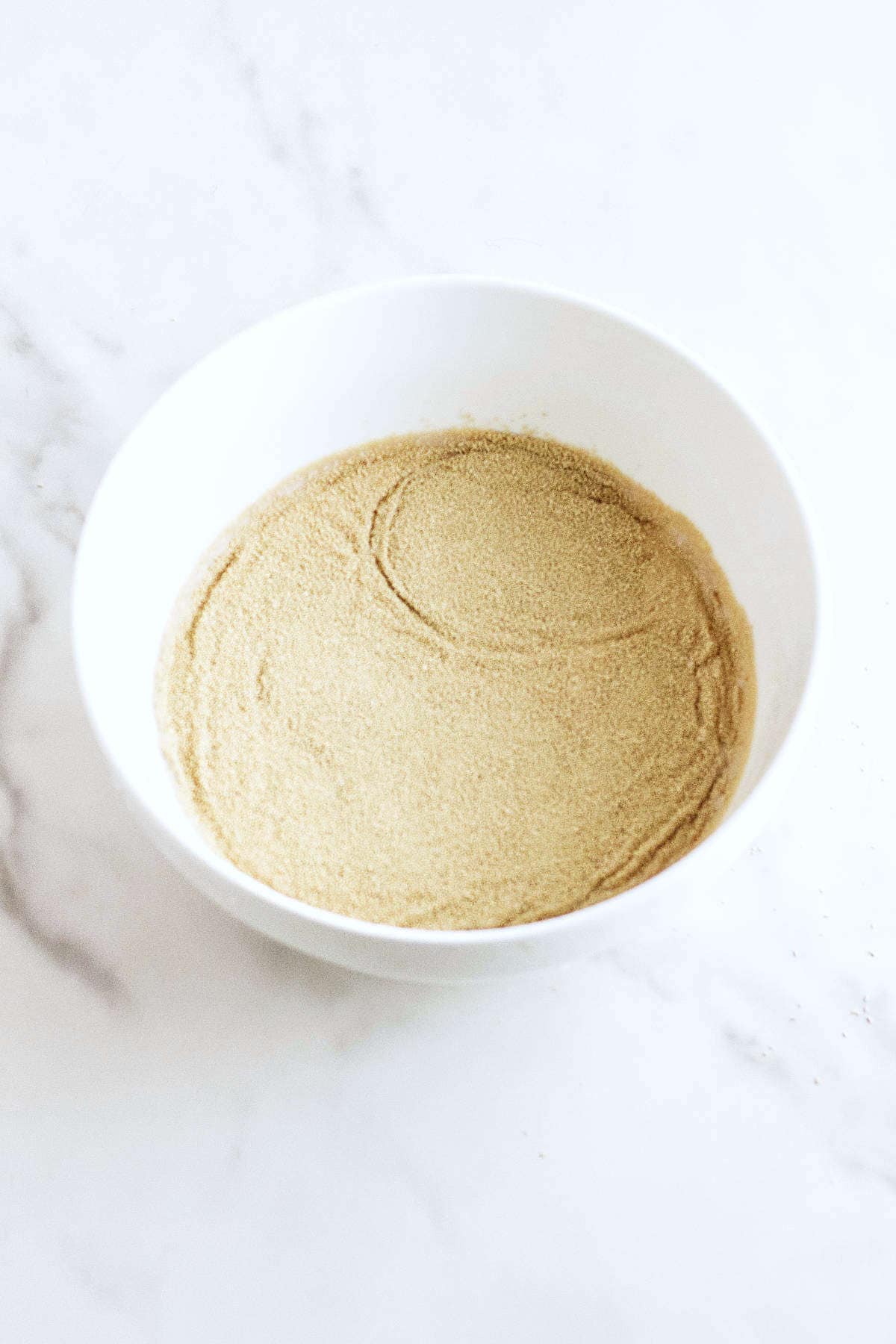 Active dry yeast sprinkled over warm liquid for Rosca de Reyes dough.