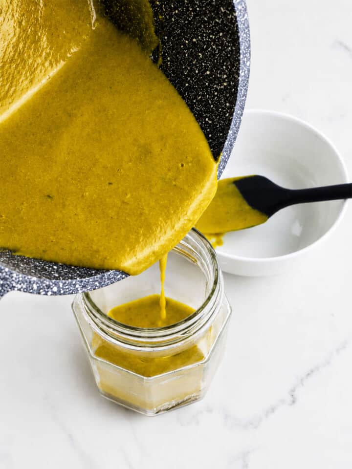 Carolina Gold BBQ sauce pouring from a saucepan into a glass jar.
