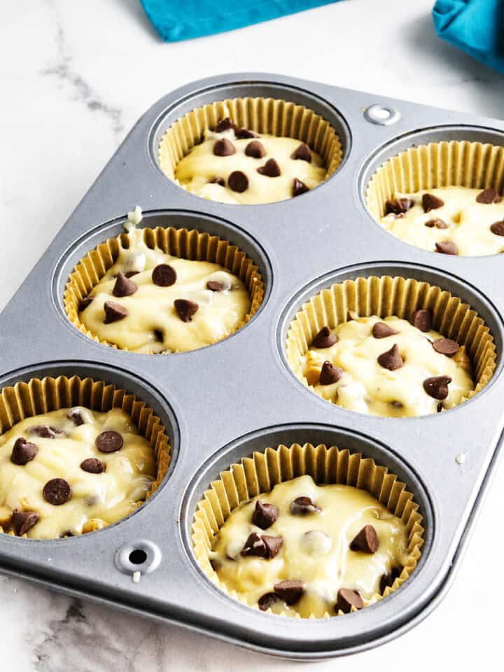 Gluten free chocolate chip muffin batter portioned into paper liners in a muffin pan.