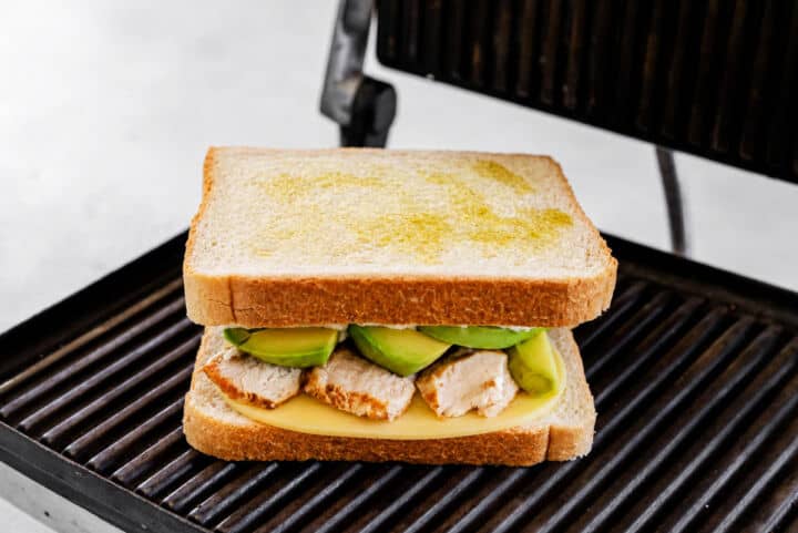 Assembled Panera Chipotle Chicken Avocado Melt on a panini press before grilling.