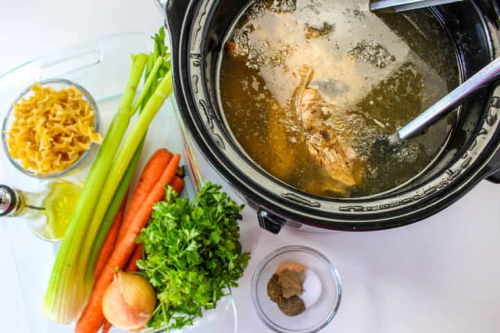 Chicken and water in a slow cooker for homemade chicken noodle soup broth.