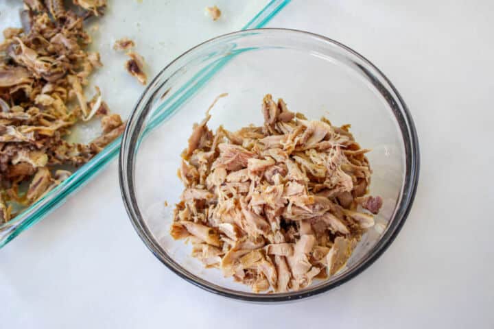 Pulled cooked chicken in a bowl for copycat Panera chicken noodle soup.