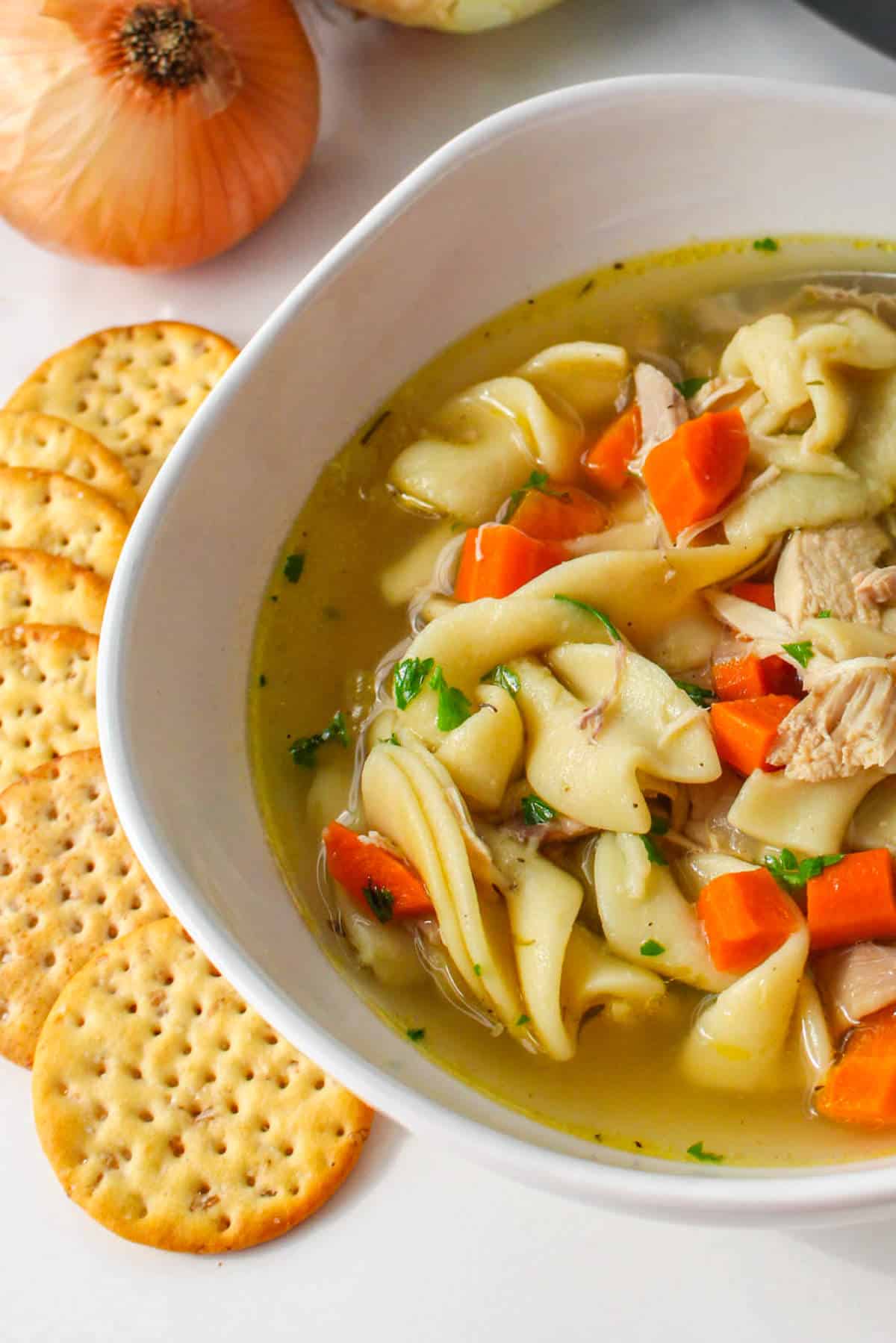 Copycat Panera chicken noodle soup in a bowl with crackers on the side.