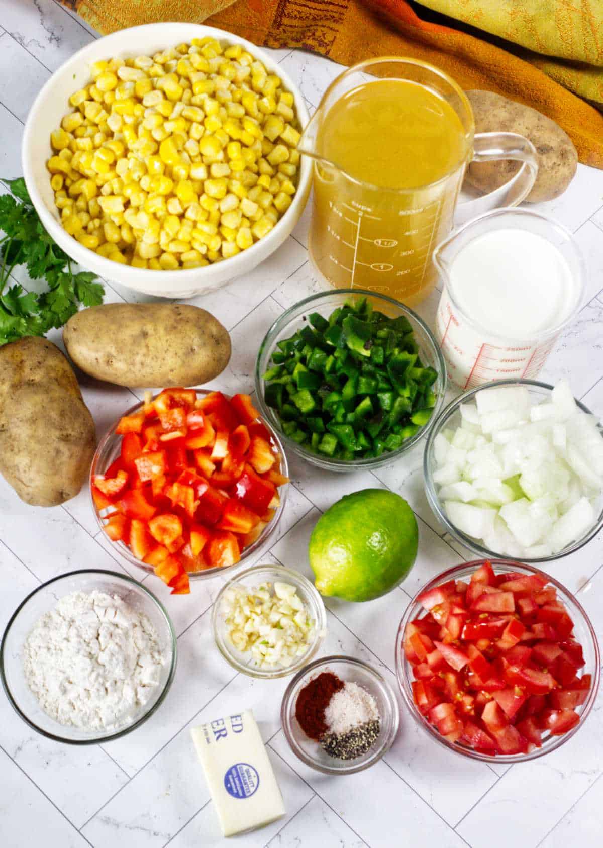 Ingredients for Panera Summer Corn Chowder with corn, potatoes, peppers, tomatoes, cilantro, cream, broth, lime, and seasonings.