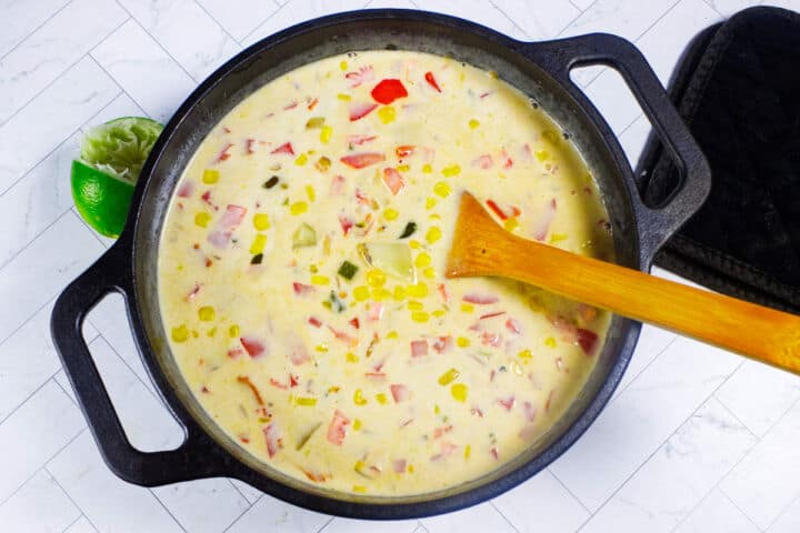 Finished Panera Summer Corn Chowder in a black pot with corn, potatoes, peppers, and cilantro.