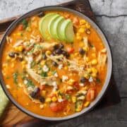 Creamy Mexican chicken enchilada black bean soup closeup on the plate on the table. Horizontal top view from above.