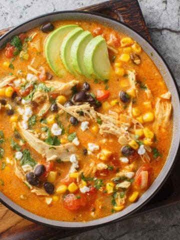 Creamy Mexican chicken enchilada black bean soup closeup on the plate on the table. Horizontal top view from above.