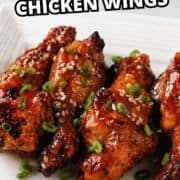 Korean soy garlic chicken wings with green onions and sesame seeds on a white plate.