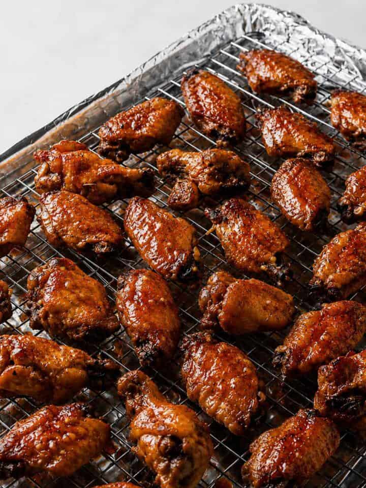 Soy garlic chicken wings coated in glaze on a wire rack before the final bake.