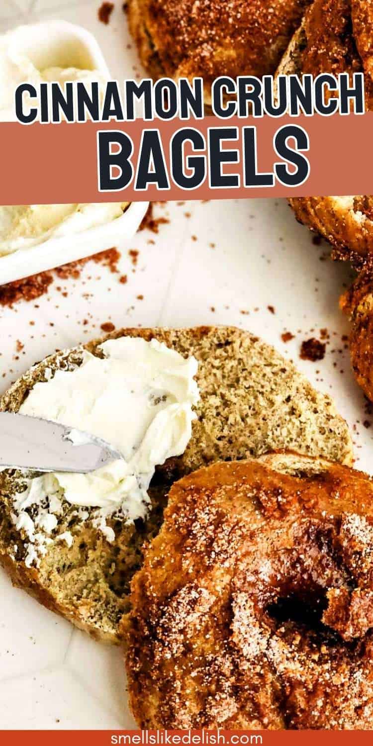 Cream cheese is spread on a sliced cinnamon crunch bagel, with whole bagels and a cream cheese container nearby.