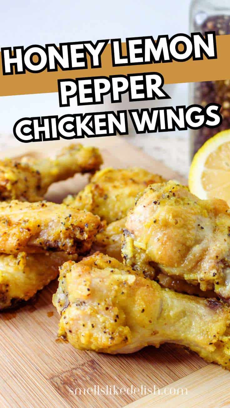 Five golden-brown chicken wings with honey lemon pepper seasoning on a wooden board, next to a sliced lemon and jar of peppercorns. Text reads: