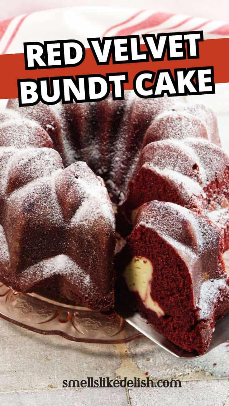 A sliced red velvet bundt cake with powdered sugar and cream cheese filling sits on a glass plate, with a red and white striped towel behind it.