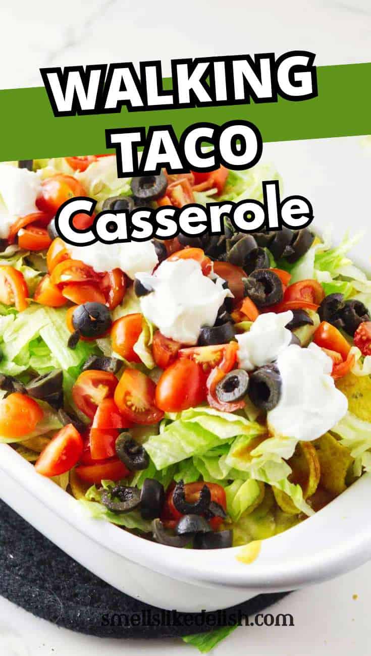 Close-up of a walking taco casserole with lettuce, tomatoes, black olives, and sour cream in a white dish. Text overlay: "Walking Taco Casserole.