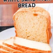 Sliced white sandwich bread on a plate with a bread machine behind it. Text: “BREAD MACHINE WHITE SANDWICH BREAD.” Website “SmellsLikeDelish.co” at the bottom.