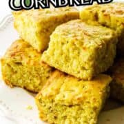 Golden square slices of Cajun cornbread are stacked on a white plate with “Cajun Cornbread” in bold text above.