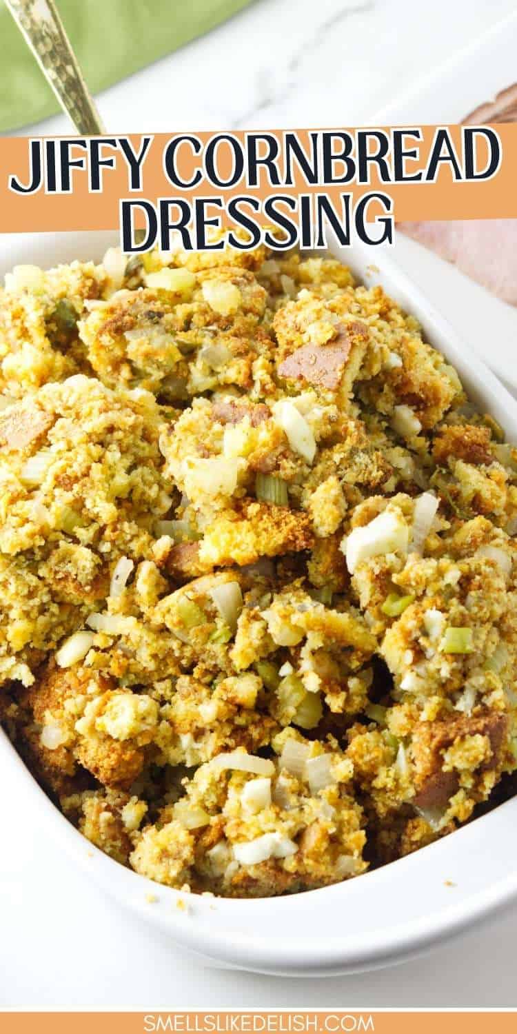 Golden Jiffy cornbread dressing with onions and herbs in a white casserole dish; spoon partially visible in the top left.