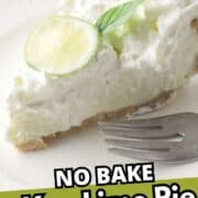 Slice of no bake key lime pie with lime and mint on top, served on a white plate with a fork. Whole lime in background. Text overlay: “NO BAKE Key Lime Pie.”.