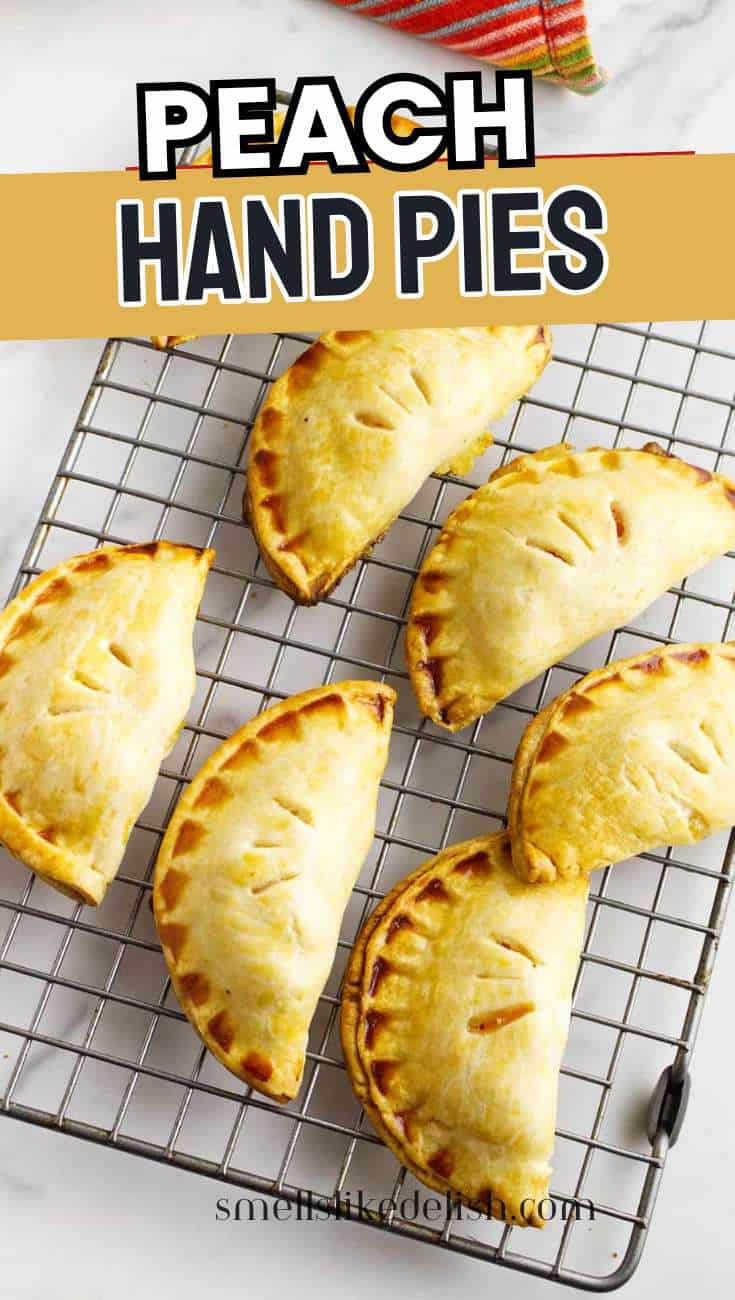 Six peach hand pies with crimped edges and slits cool on a wire rack; colorful cloth in background and
